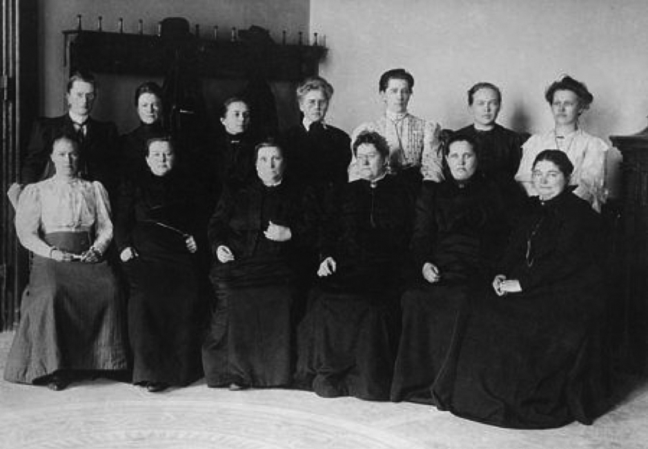 Figure 6.0: Caption: Finland, 1907: the world’s first female Members of Parliament
Notes: Pictured seating from left to right are: Hilja Pärssinen, Alli Nissinen, Lucina Hagman, Alexandra Gripenberg, Evelina Ala-Kulju ja Liisa Kivioja. Standing, from left, are: Dagmar Neovius, Hedvig Gebhard, Iida Vemmelpuu, Hilda Käkikoski, Miina Sillanpää, Hilma Räsänen, Maria Laine. 
In 1906 Finland was still an autonomous Grand Duchy of the Russian empire, but its national assembly granted universal suffrage to all adult men and women, including not only the right to vote, but also to stand for election. In 1907, 19 women, most of whom are shown in this photograph taken that year, were elected to Finland’s single-chamber parliament. Among them was Miina Sillanpää, who in 1927 became the first female minister and was a Member of Parliament for 38 years. In 2016 the government made 1 October a flag day to honour her (Korpela, 2006).
Source: Helsinki City Museum (2019) (photographer unknown) and as reported by mtv uutiset in: 110 Years of Women's Suffrage Here are the first women MPs in the world, accessed 17 November 2019:  https://www.mtvuutiset.fi/artikkeli/naisten-aanioikeudesta-110-vuotta-tassa-ovat-maailman-ensimmaiset-naiskansanedustajat/5922610#gs.dqorhm
More information is available here: https://finland.fi/life-society/real-bridge-builder-became-finlands-first-female-government-minister/